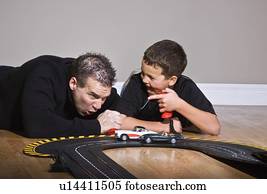 Father and son playing with race track