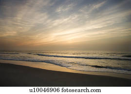 Ocean waves lapping on the shore at sunset.