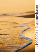 Waves lapping on beach at sunset.