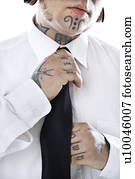 Caucasian mid-adult man with tattoos and piercings adjusting necktie.