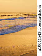 Waves lapping on beach at sunset.