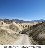 Dirt road through barren landscape in Death Valley National Park.