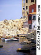 Beachside housing , red yellow white  with boats in water and rocky outcrop Elba Italy