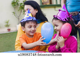 Boy and a girl playing with balloons and their mother sitting beside them