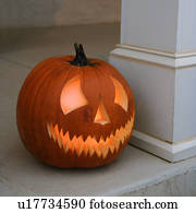 Carved Halloween pumpkin sitting on doorstep.